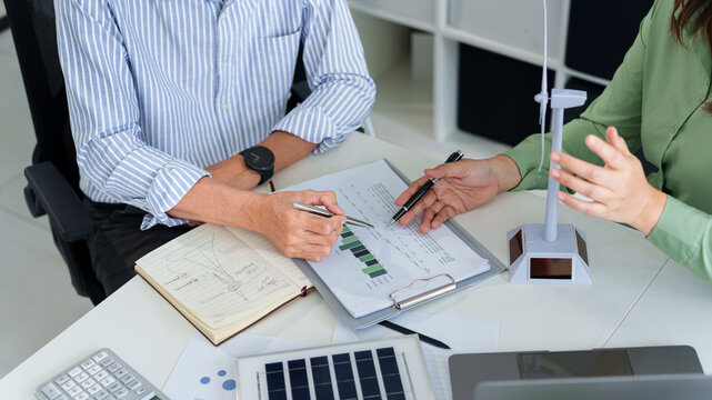 Hands of adult Asian business professionals analyzing ESG financial data and renewable energy project plans