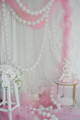 a cake made of marshmallows stands on a table in a pink studio or room decorated with balloons for a boy or girl's birthday celebration