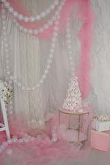 a cake made of marshmallows stands on a table in the pink decorations of a studio or room decorated for a boy or girl's birthday celebration