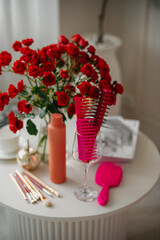 a bouquet of red roses on a table next to a set of hair combs, makeup brushes and hair and skin care products in bottles