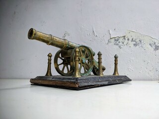 Antique brass artillery cannon still life on a distressed white table with grunge texture...