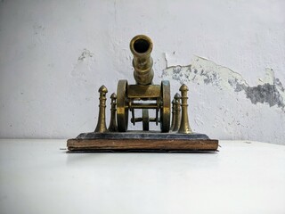 Antique brass artillery cannon still life on a distressed white table with grunge texture background. Front View