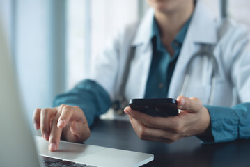 Medical technology concept. Doctor working on laptop computer, using mobile phone  in doctor office...