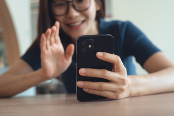 Close up, happy relaxed young asian woman using cell phone. Smiling woman holding smartphone, looking at the screen enjoying video call with her friend or watching video at home