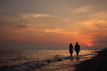 Obraz premium A serene sunset walk along a secluded beach, with soft waves gently lapping at the shore. 