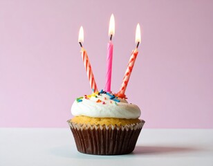 Lit candles top a frosted cupcake, vibrant against pink backdrop