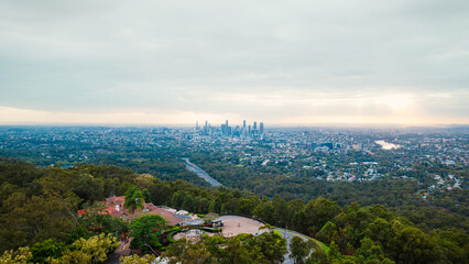 Brisbane skyline rising above lush green forest at sunset