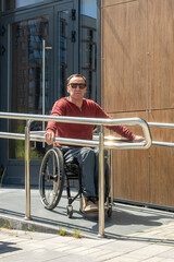 A middle -aged man in a wheelchair independently descends along the ramp