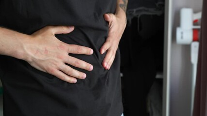 An adult man in a black sweatshirt is experiencing pain in his stomach and massages it with his hands.
Pain and spasm in the intestines.
Food poisoning and intestinal pain