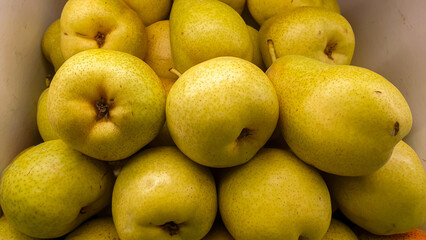 Close-up of a pile of ripe pears, showcasing their natural yellow hue and textured skin, ideal for healthy eating and produce themes