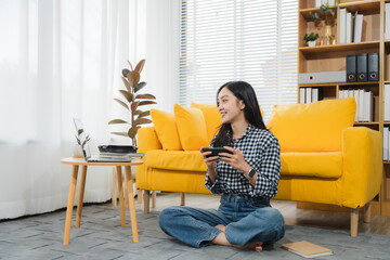 Serene Gamer Girl: An Asian woman enjoys leisure in a cozy living room, immersed in a virtual game...
