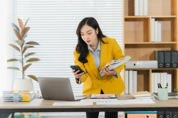 Focused Professional at Work: A driven woman concentrates on a call and manages documents,...