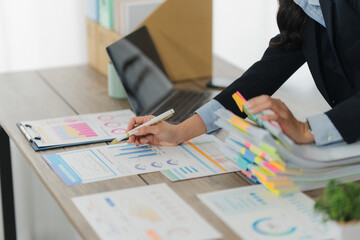 Office Analysis: A close-up shot of hands meticulously reviewing charts, graphs, and documents at a...