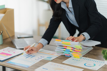 Businesswoman reviewing documents: A focused businesswoman meticulously reviews important financial...