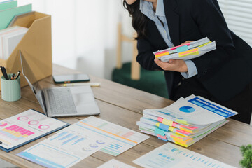 Businesswoman Reviewing Documents: A focused businesswoman meticulously examines a stack of...