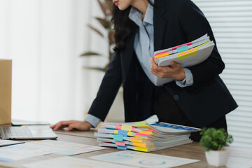Businesswoman reviewing documents: A focused businesswoman meticulously reviews a stack of...