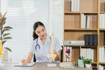 Doctor Examining Spine Model: A focused female doctor meticulously examines a detailed anatomical...