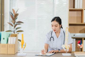 Focused Physician: A concentrated female doctor meticulously reviews patient files, showcasing her...