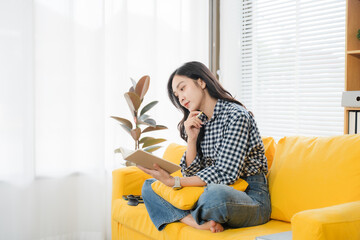 Solitude's Embrace: A young woman, lost in the pages of a book on a vibrant yellow sofa, finds...