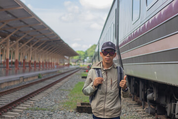 Confident young latin man standing alone at sunrise. Standing on train station platform, holding...