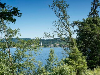 Titisee im Südschwarzwald in Baden-Württemberg. Entlang des Seerundwegs mit Blick auf die katholische Pfarrgemeinde und Christkönigkirche in Titisee-Neustadt am Nordufer des Sees

