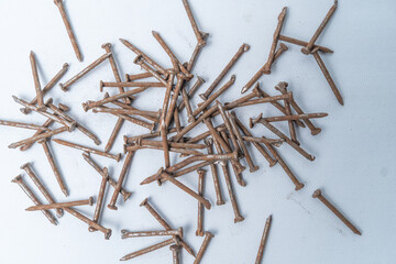 Close-up of a pile of rusty nails scattered on a white surface. Great for construction, DIY,...