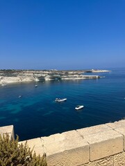 Obraz premium Ocean view from coastal cliffs with boats anchored in clear waters on a sunny day