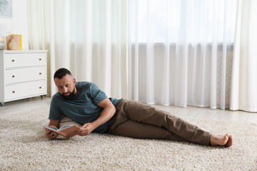 Harmony. Man reading book on rug at home
