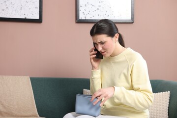 Young woman with bag complaining to customer service via phone at home