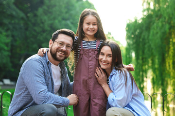 Naklejka premium Family portrait of smiling parents and daughter in park