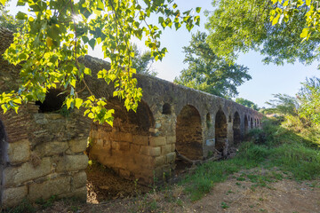Ancient Roman bridge with arches illuminating the Cuba landscape in Beja, Portugal