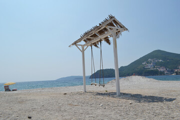 Charming Beach Swing with Thatched Roof on a Scenic Montenegro Beach, Overlooking the Adriatic Sea...