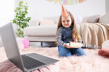 Birthday celebration. Little girl with piece of cake having video call via laptop at home