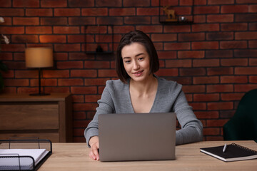 Smiling woman working with laptop at desk in home office