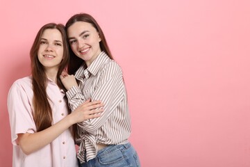 Friends hugging each other on pink background, space for text
