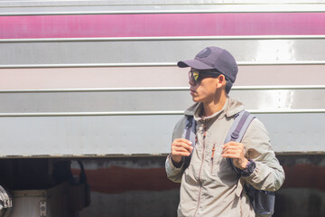 Confident young latin man standing alone at sunrise. Standing on train station platform, holding...