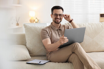 Professional psychologist having online consultation with his client via laptop on sofa indoors