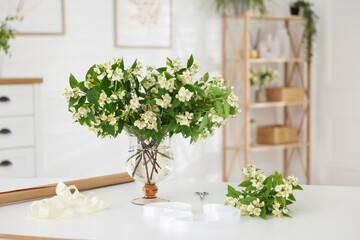 Bouquet of beautiful jasmine flowers in vase on white table indoors