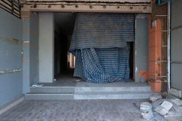 Abandoned building entrance under renovation or demolition, covered with dusty striped tarp....