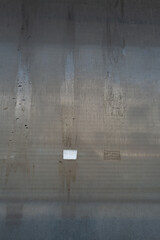 Weathered metal surface with vertical dirt streaks and remnants of adhesive marks. A minimalist...