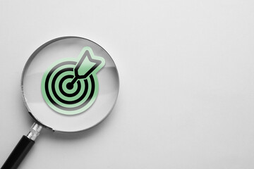 Magnifying glass over target with arrow on white background, top view