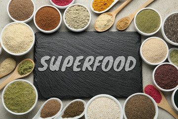 Different superfoods and slate board on grey table, flat lay