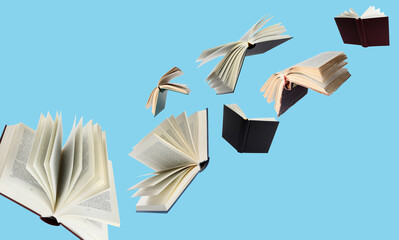Hardcover books flying like birds against light blue background