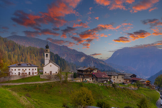 Sauris di Sopra glowing under colorful clouds at sunrise in Friuli, Italy