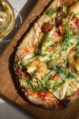 Pinsa with shrimp, zucchini and pesto on wooden board
