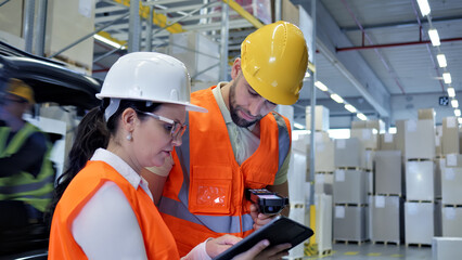 In a busy cargo warehouse, two workers in white and yellow helmets collaborate, focused on a tablet and scanner. Their precision and teamwork ensure efficient global supply chain logistics.