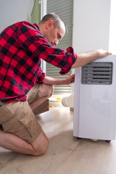 A white man installing a portable air conditioner at home, close-up