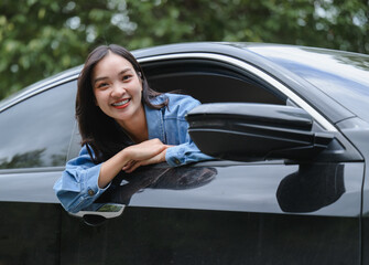 Happy young woman leaning out of car window enjoying road trip