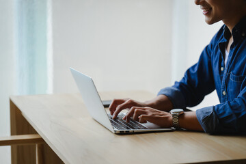 Smiling young businessman working on laptop at home office