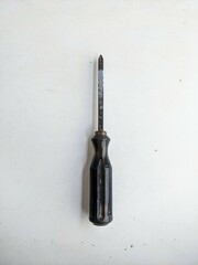 Old and used Phillips head screwdriver with a dark handle, isolated on a white grunge background. Vintage handyman tool for repair.